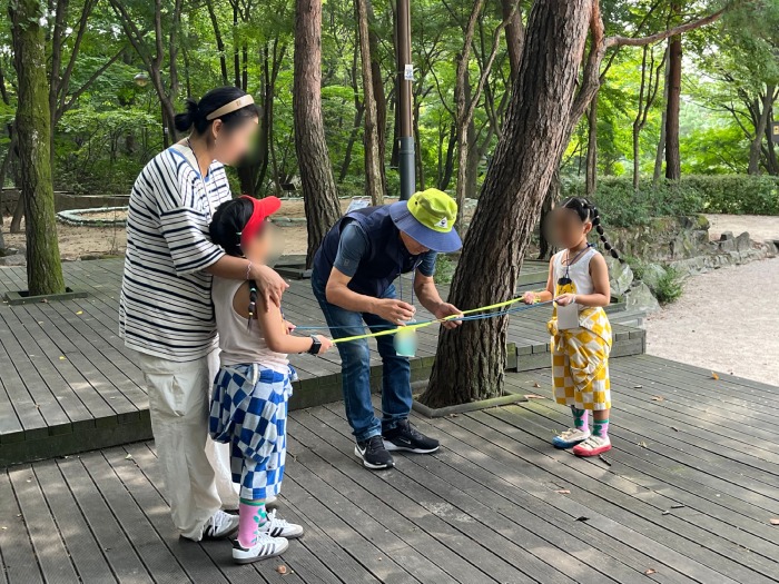 끈 사이에 고무줄을 끼우고 솔방울을 올려 게임을 진행할 준비를 함